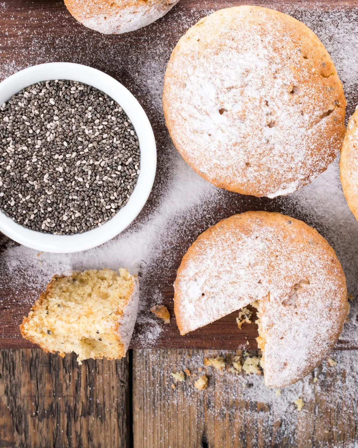 Muffins on a board beside a bowl of chia seed