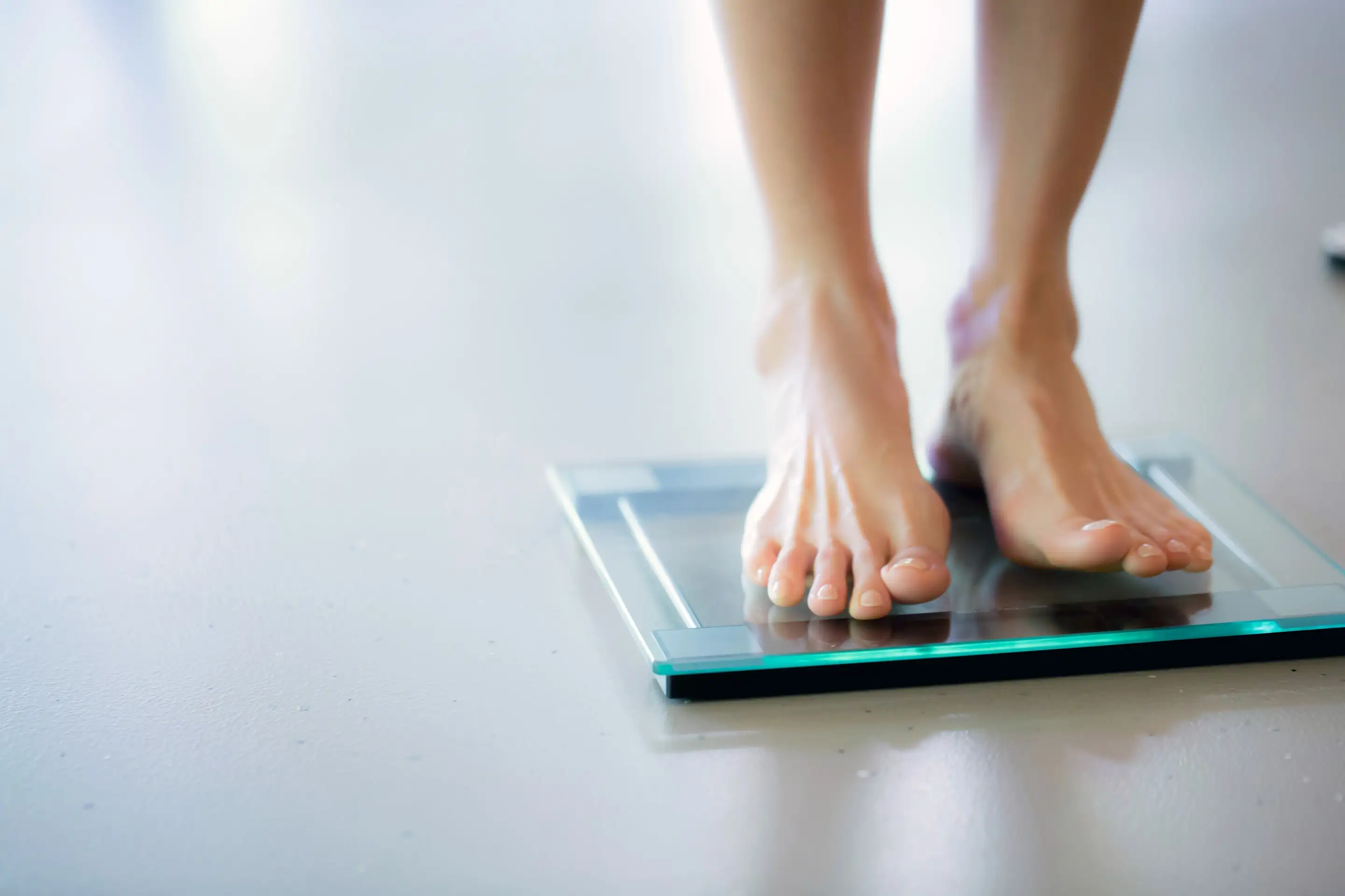 A person's feet on a glass bathroom scale