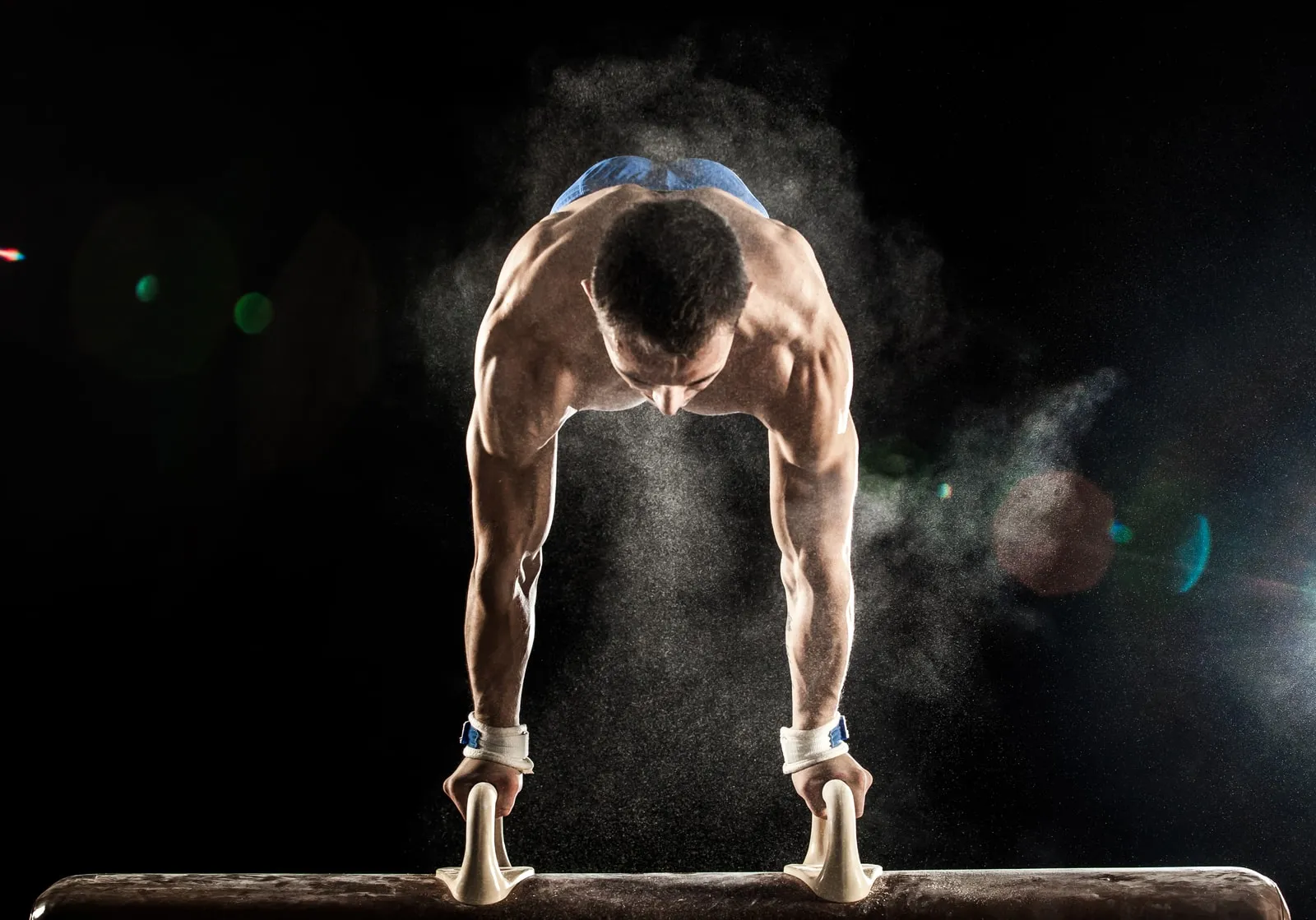 A gymnast holding a handstand on a pommel horse