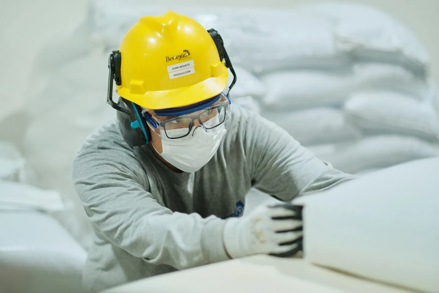 An operator in a hard hat handling a bulk bag of chia seed